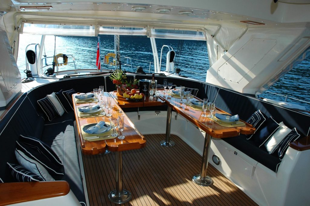 Pont de yacht luxueux avec une table à manger élégamment dressée donnant sur la mer tranquille.